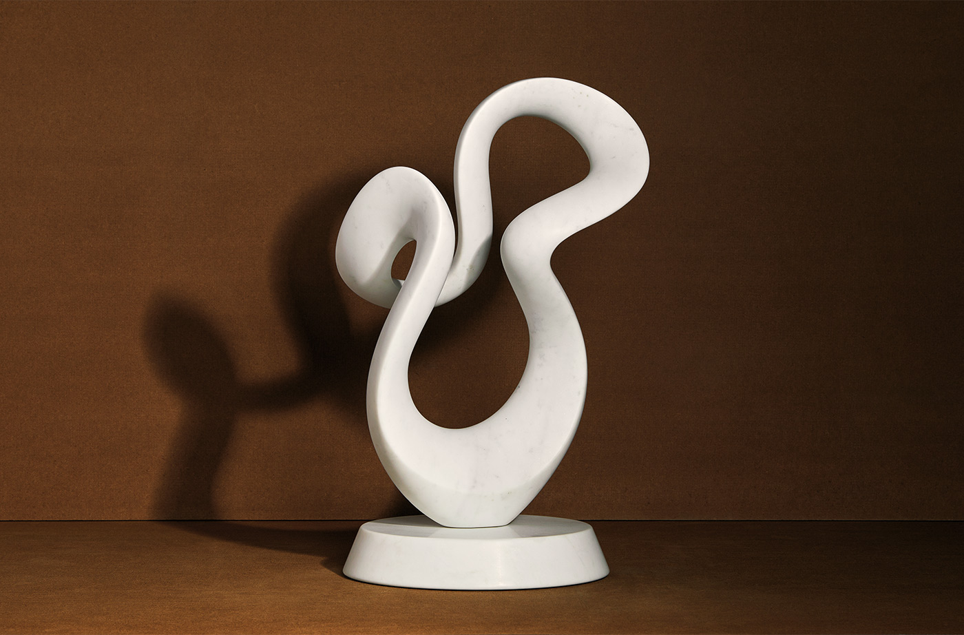 white marble abstract sculpture in front of brown background