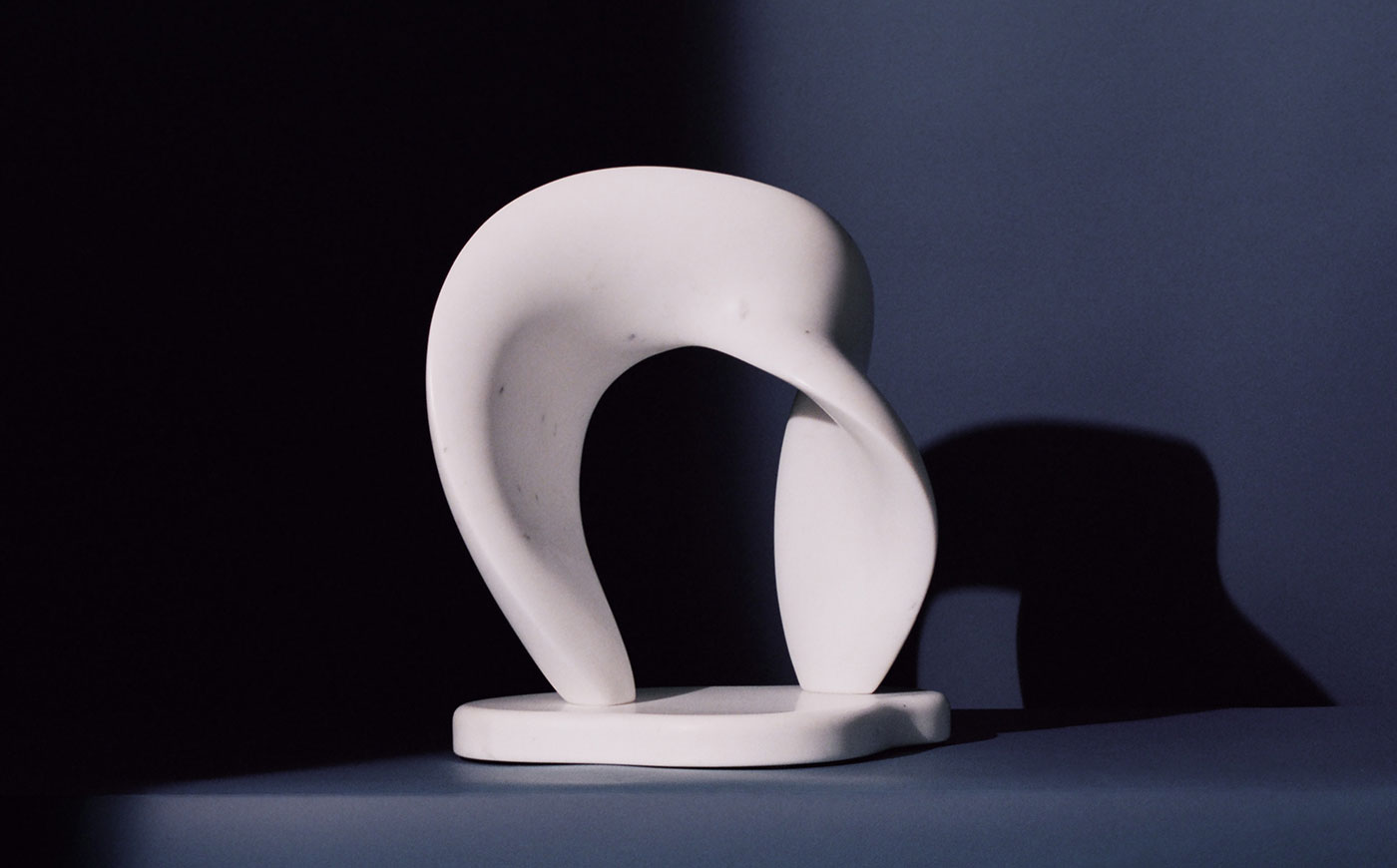 contemporary abstract modern sculpture like a twisted archway with smooth marble planes on a blue backdrop