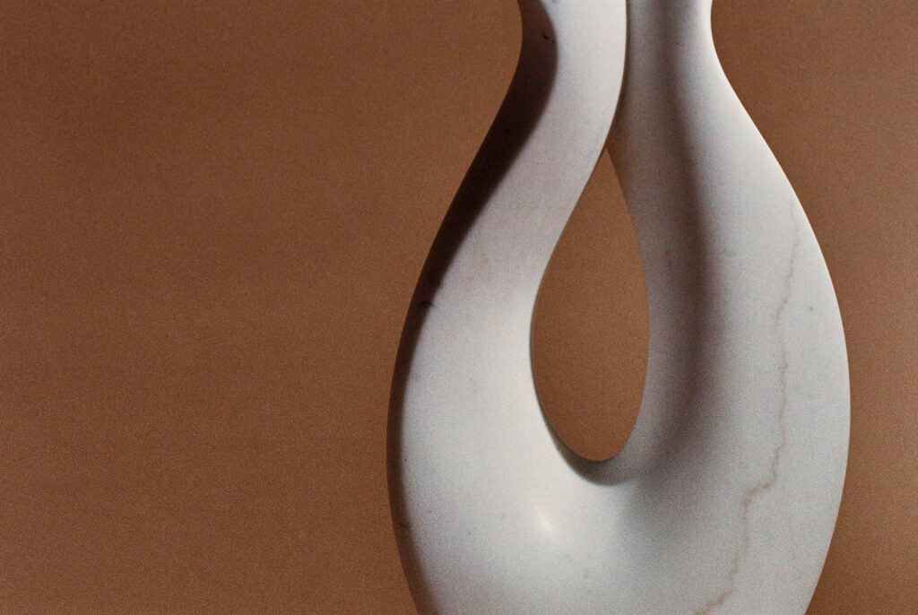 white marble abstract sculpture in from of a brown background