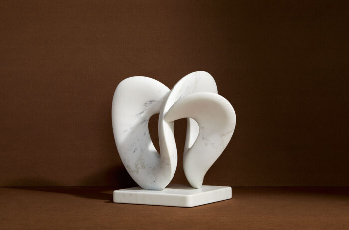 modern abstract marble sculpture in front of brown background